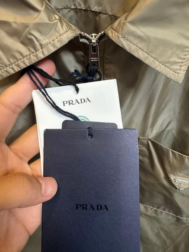 左胸口袋上带有品牌标志性的金属三角徽标，是整件夹克的灵魂亮点。