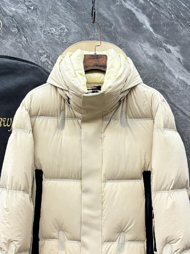 这款羽绒服的面料选用了客供定制的高密度轻质尼龙，这种面料不仅轻盈如羽