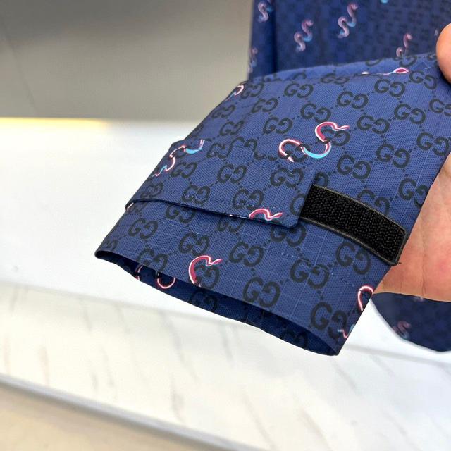 经典深蓝底料密布GUCCI标志性暗纹，粉蓝双色灵蛇蜿蜒游走，