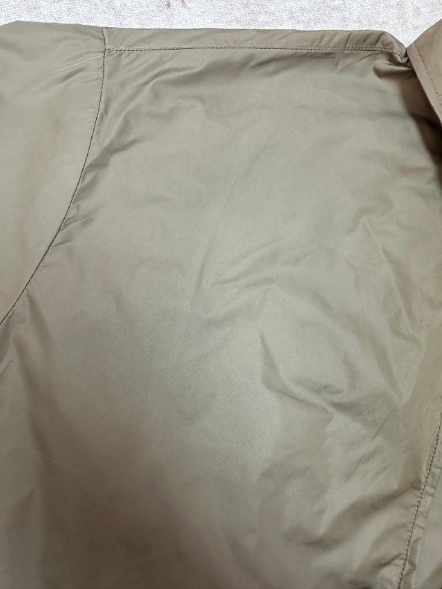 左胸口袋上带有品牌标志性的金属三角徽标，是整件夹克的灵魂亮点。