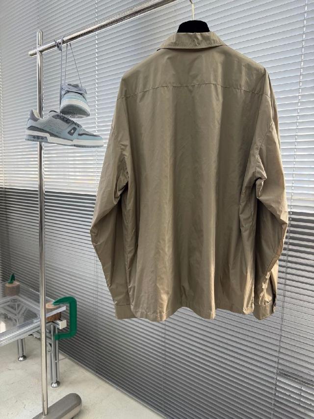 左胸口袋上带有品牌标志性的金属三角徽标，是整件夹克的灵魂亮点。